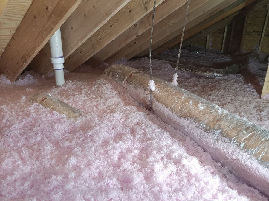 Blown fiberglass insulation covering an attic floor around insulated flex ducts