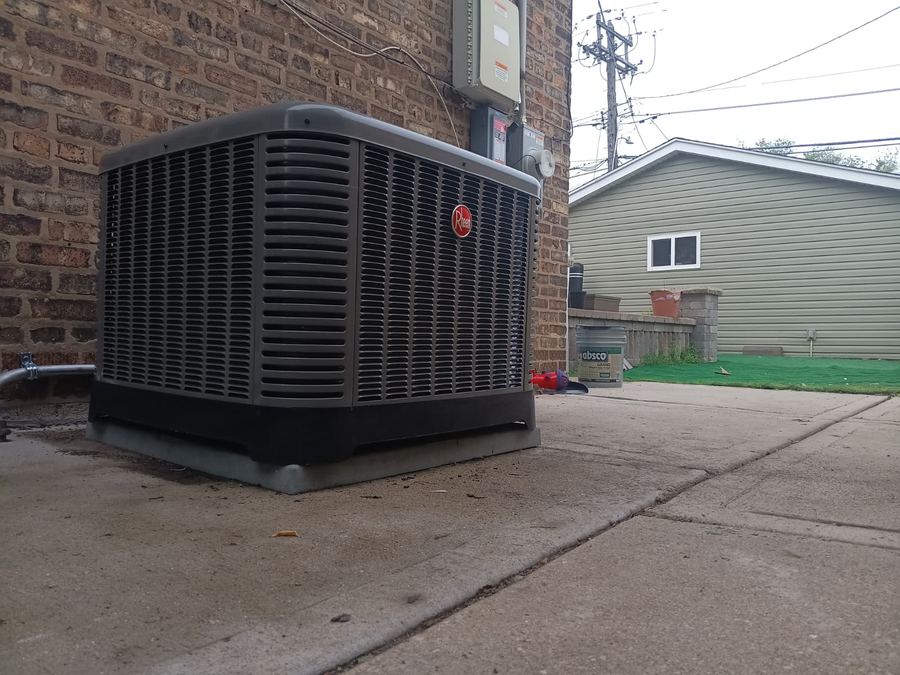 Large Rheem condenser unit installed on a pad beside a brick Chicago home