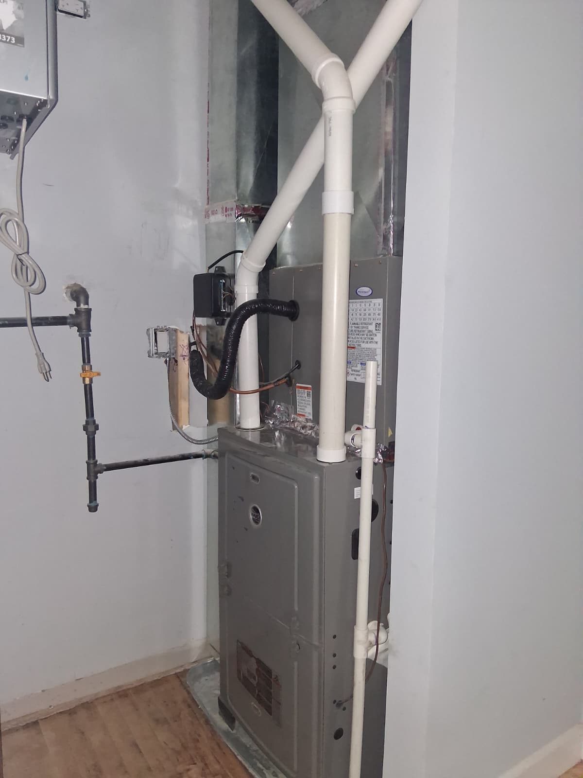 High-efficiency gas furnace installed in a residential utility closet with PVC venting