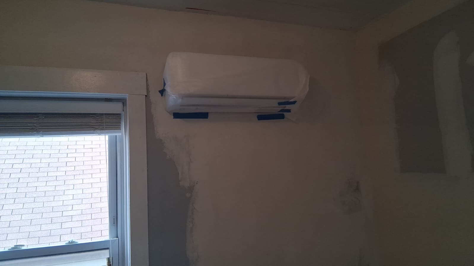 Wall-mounted ductless mini-split indoor unit installed near a window